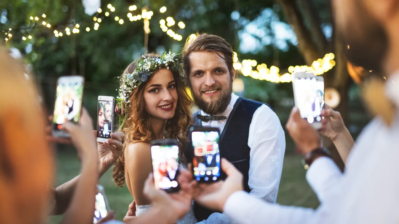 Gäste machen Bilder am Hochzeitstag vom glücklichen Brautpaar